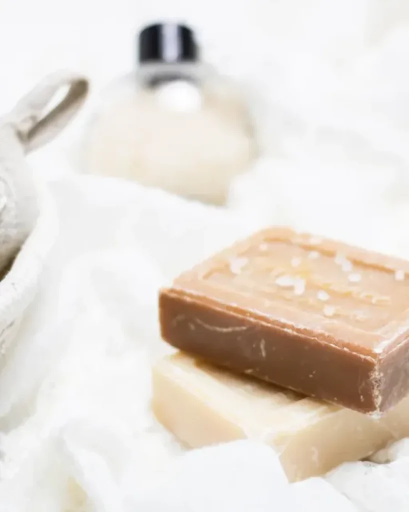 Bars of soap on soft white linen with a wooden brush and a glass bottle