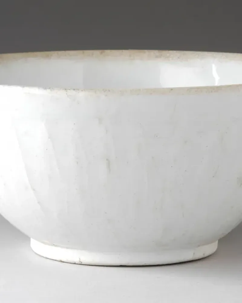 A plain white ceramic bowl on a light grey background
