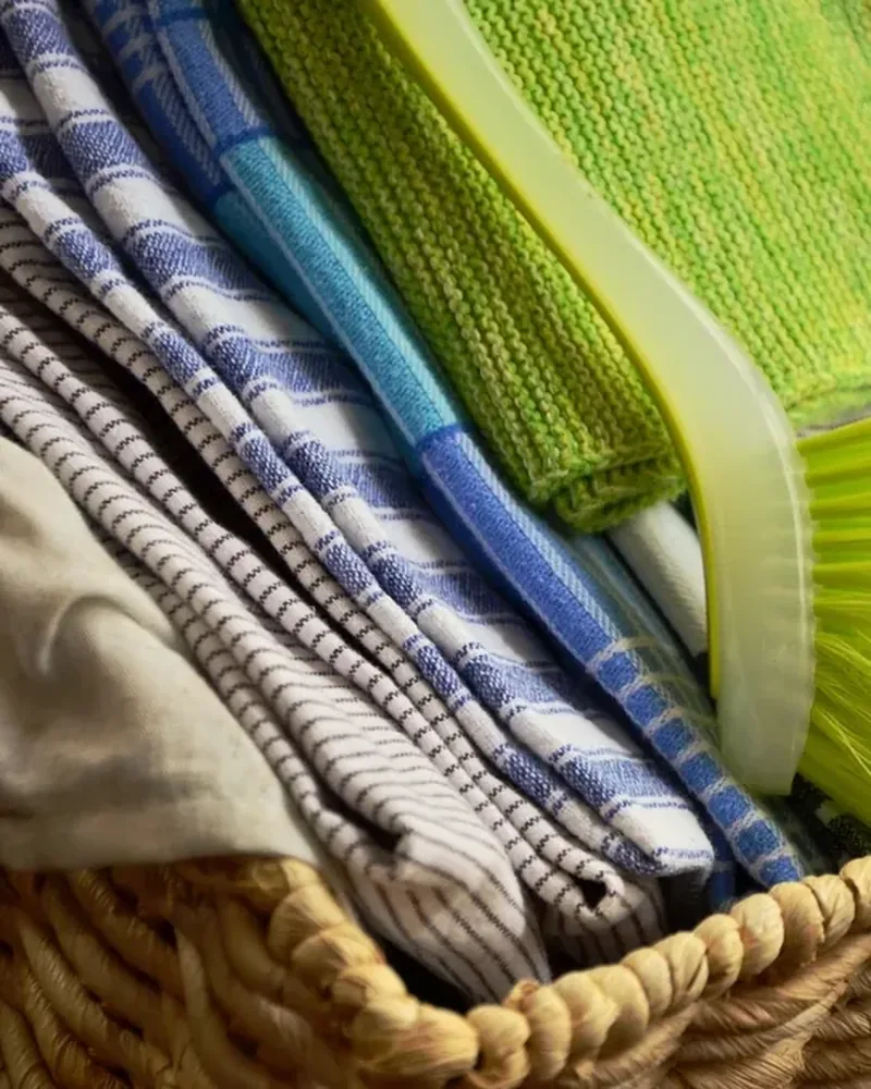 Folded striped cotton kitchen towels in a woven basket