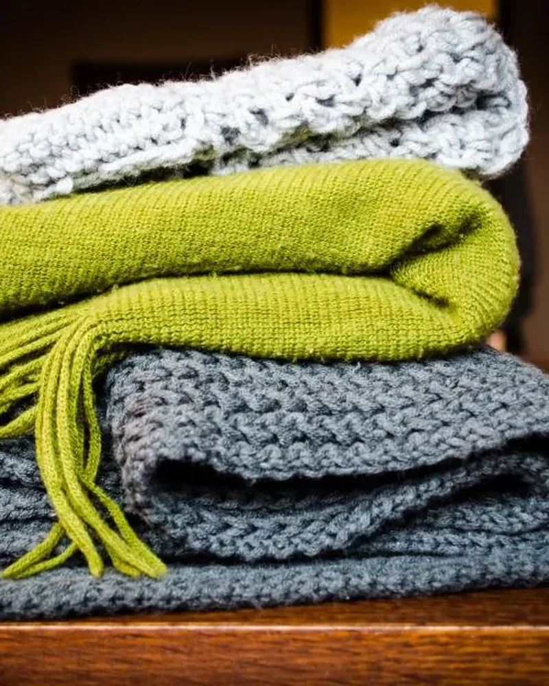 Folded textured throws in green and grey stacked on a table
