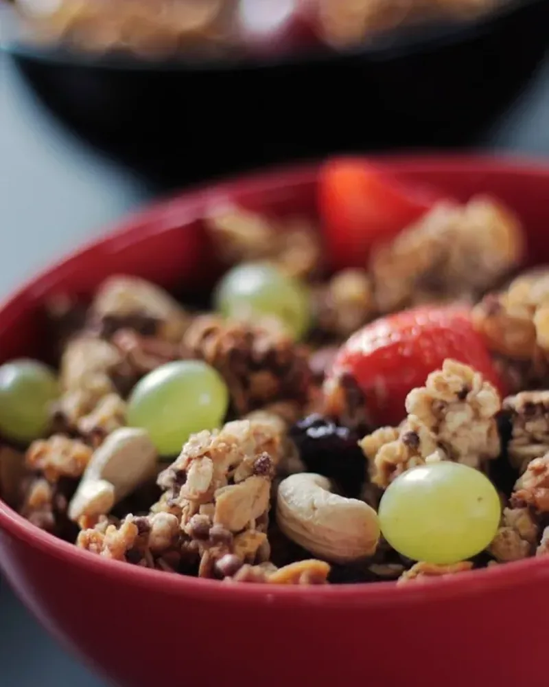 Granola with fruit and nuts in a red glazed bowl
