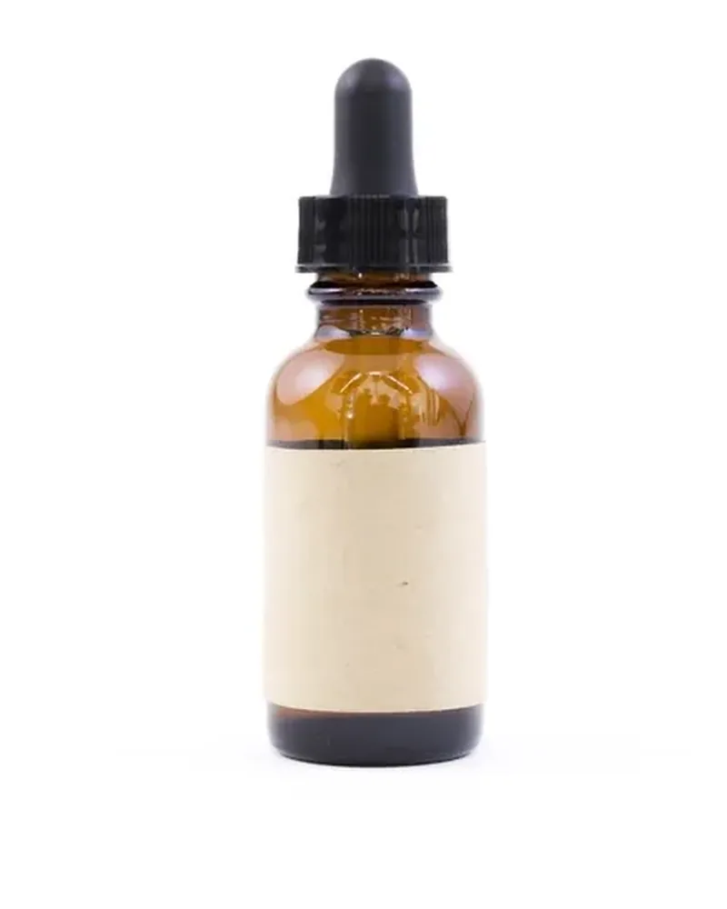 An amber glass dropper bottle with a blank label on a white background