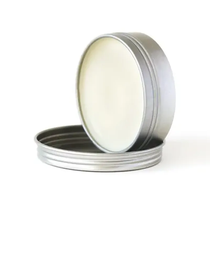 An open round metal tin of balm on a white background
